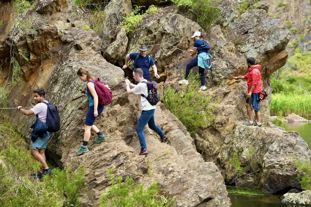 Social Hikes Australia group scrambling over rocks beside the river in Werribee Gorge